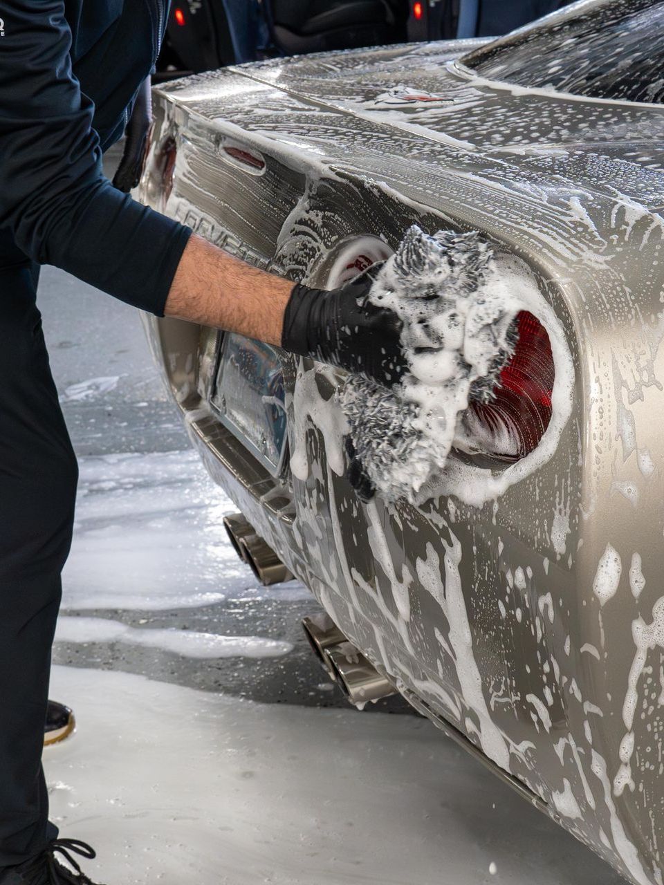 A man is washing a car with soap and water.