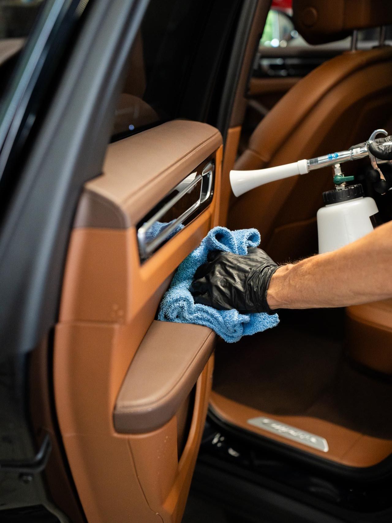 A person is cleaning the interior of a car with a spray bottle.