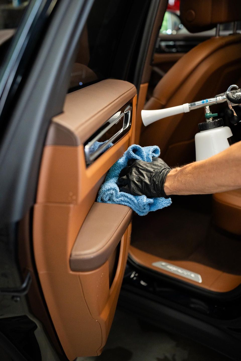A person is cleaning the interior of a car with a spray bottle.