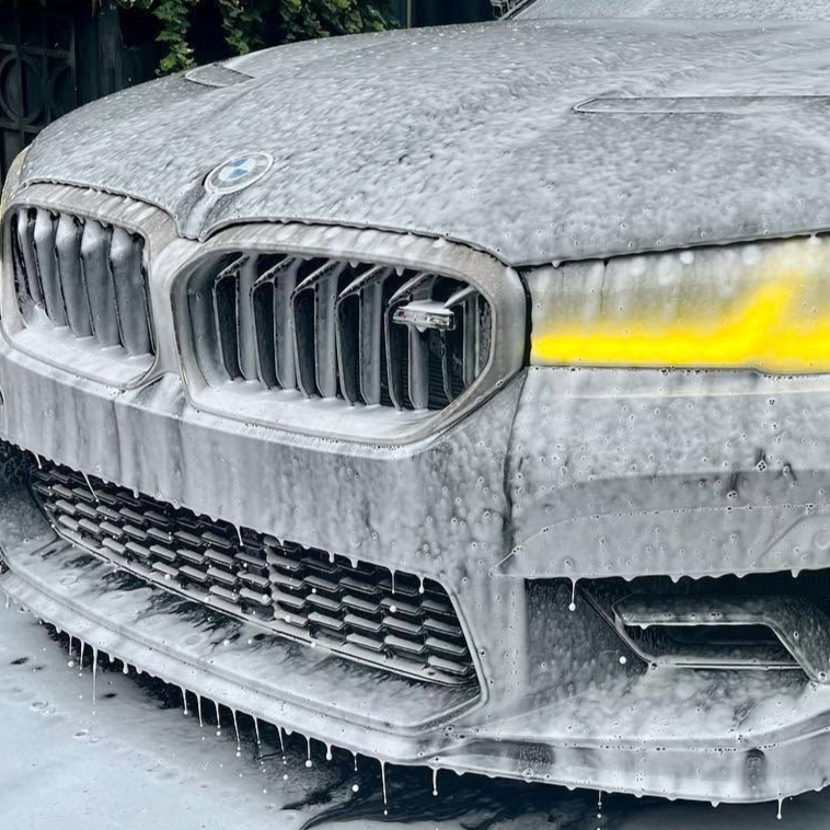 A person wearing blue gloves is cleaning the headlight of a car