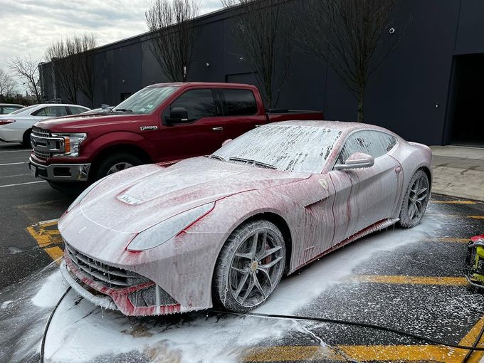 A car is covered in foam in a parking lot next to a truck.