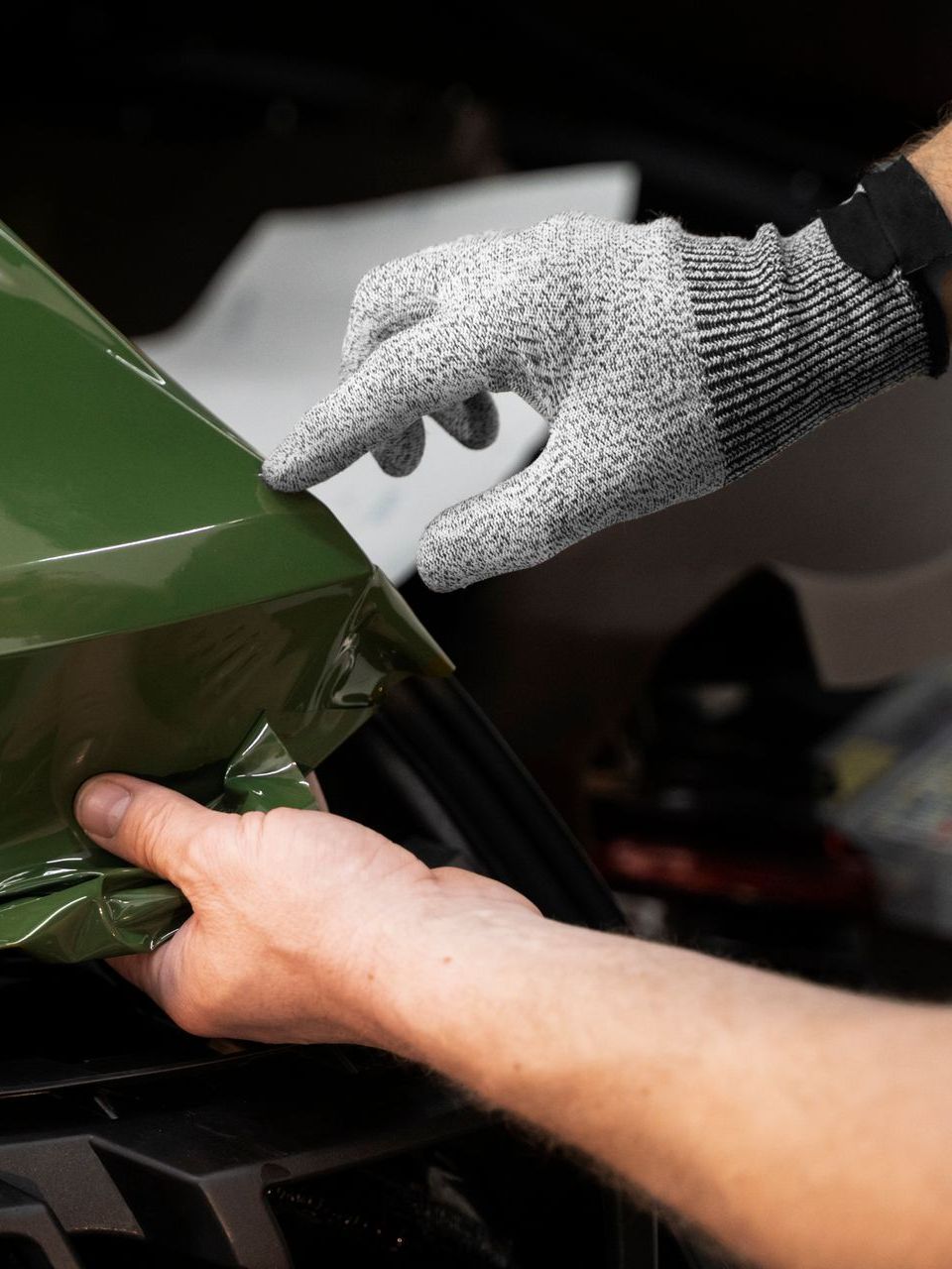 A person wearing a glove is touching a green object