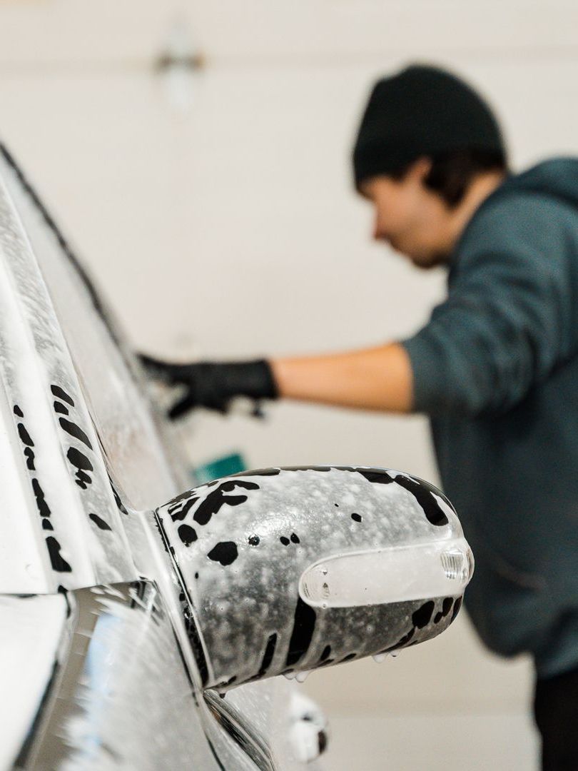 A man is washing a car with soap and water