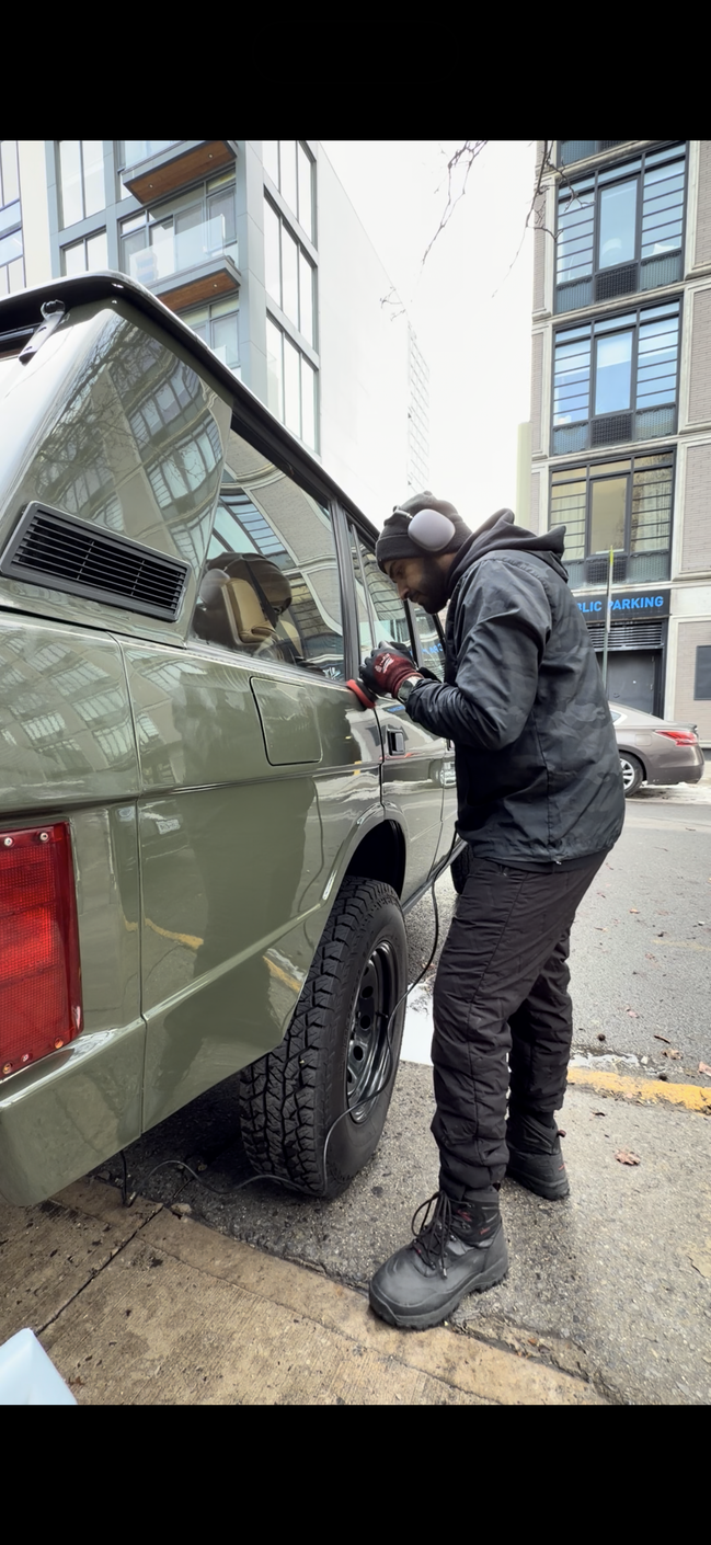 A person is cleaning the air vent of a car with a brush.
