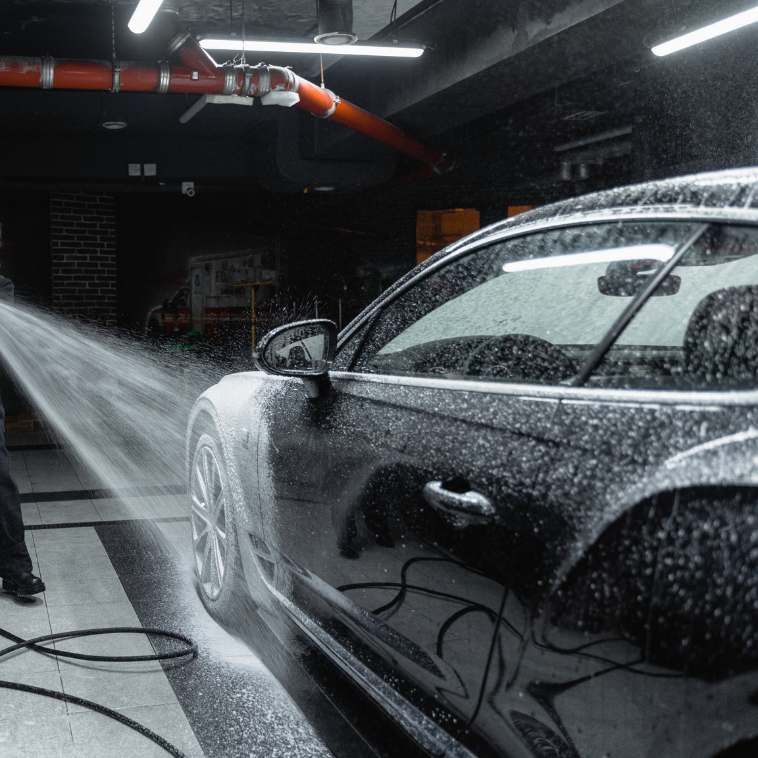 A person wearing blue gloves is cleaning the headlight of a car