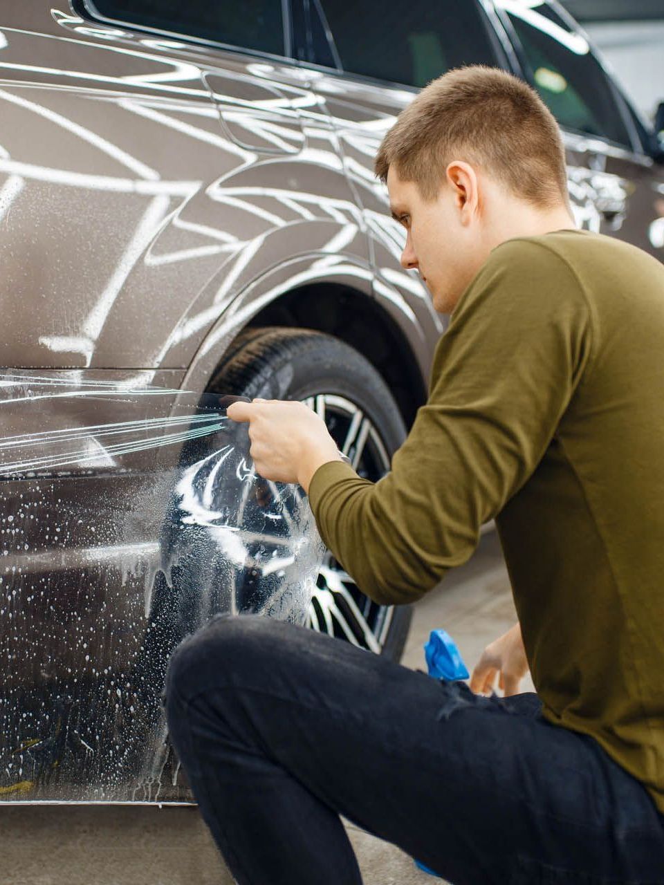 A man is cleaning a car with a brush.