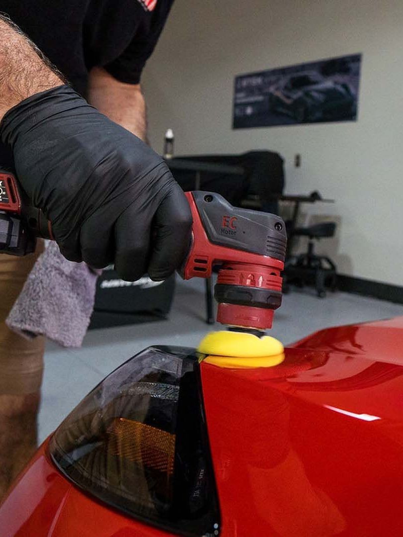 A person is polishing a car with a machine.