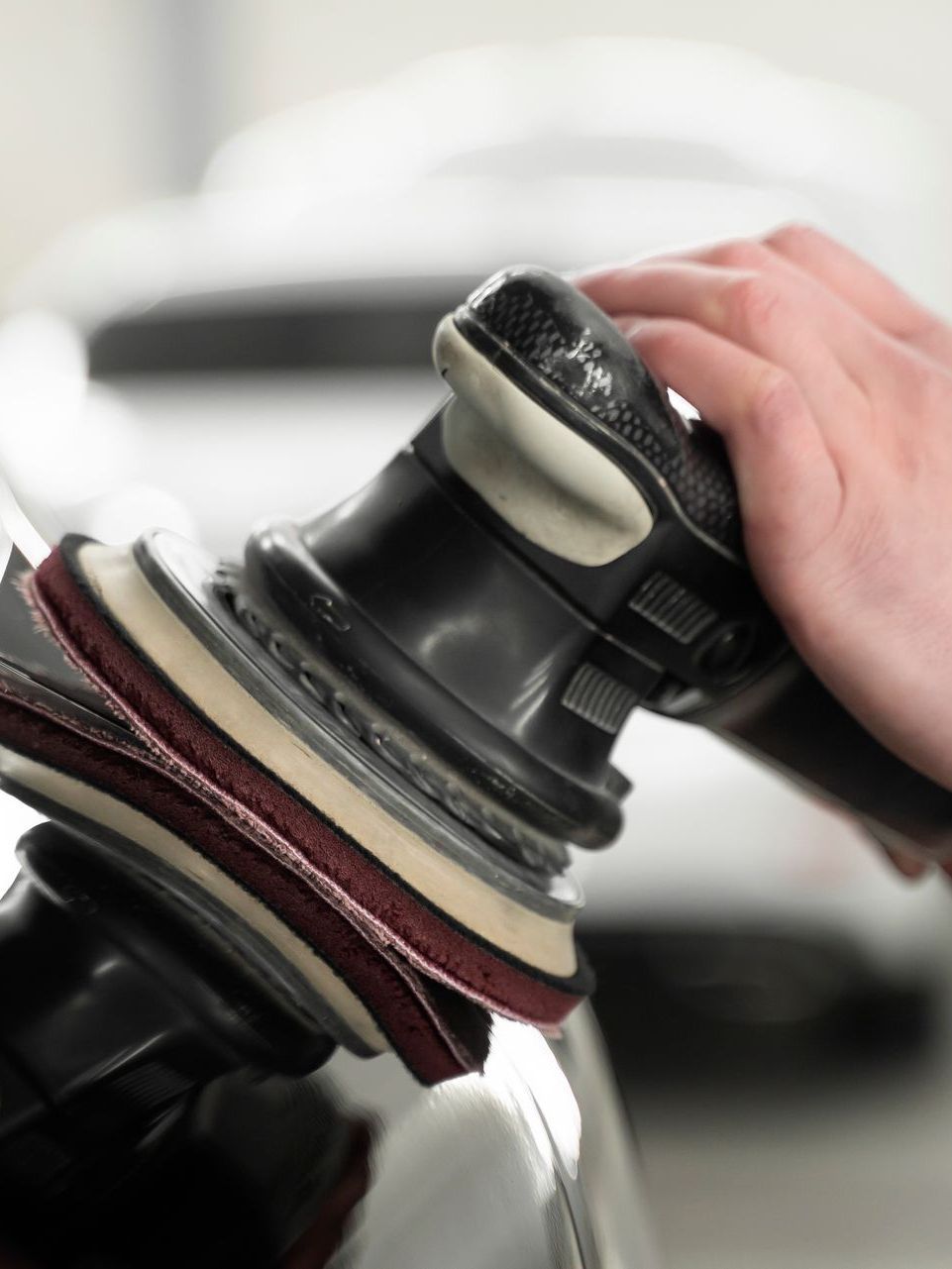 A person is polishing a car with an orbital sander