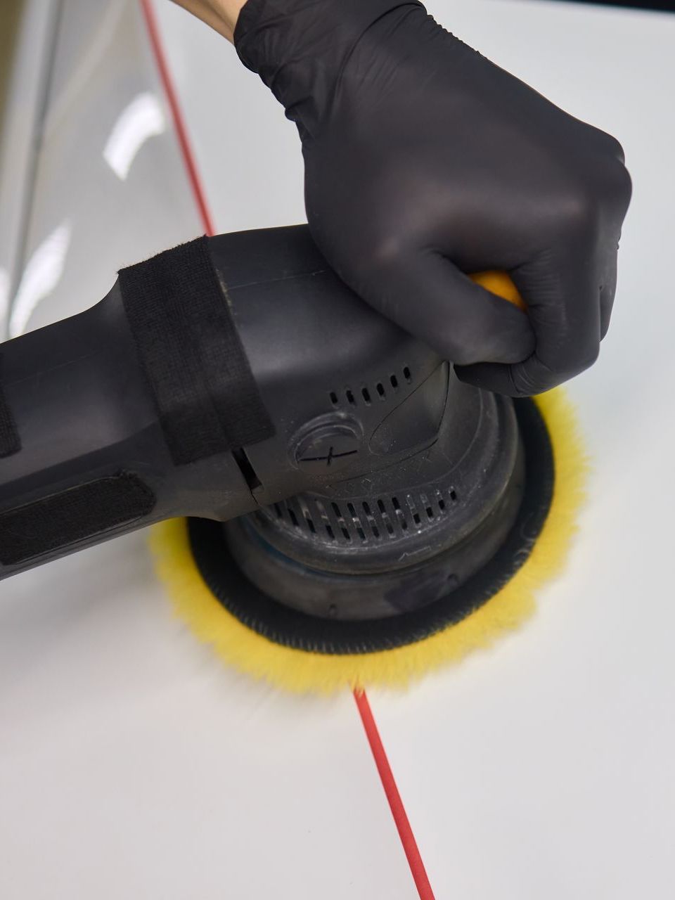 A person wearing black gloves is polishing a car