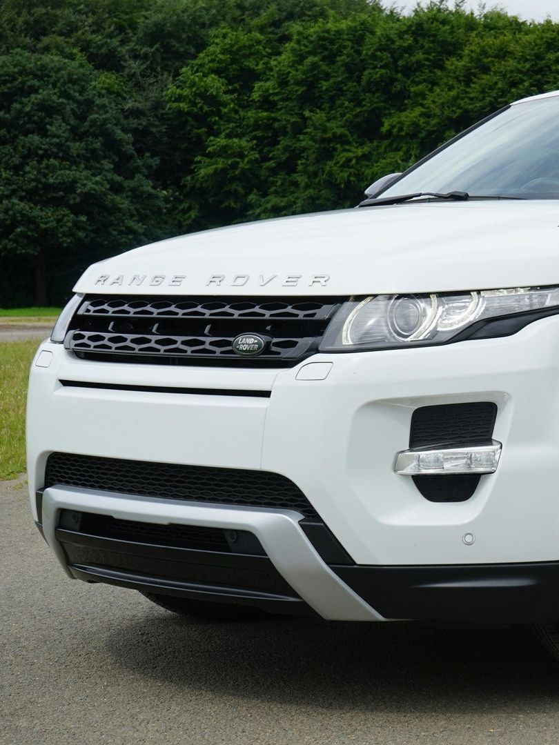 A white range rover is parked on the side of the road