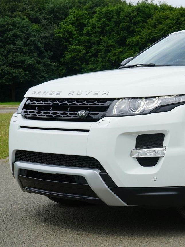A white range rover is parked on the side of the road