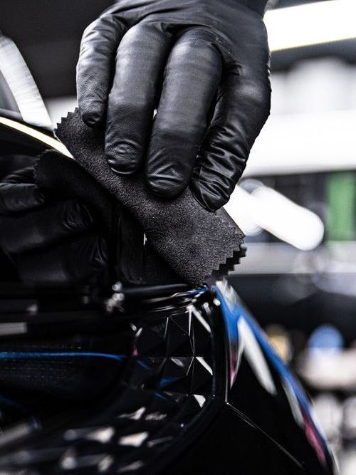 A person is cleaning the air vent of a car with a brush.