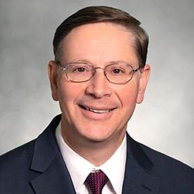 A man in a suit and tie is smiling for the camera.