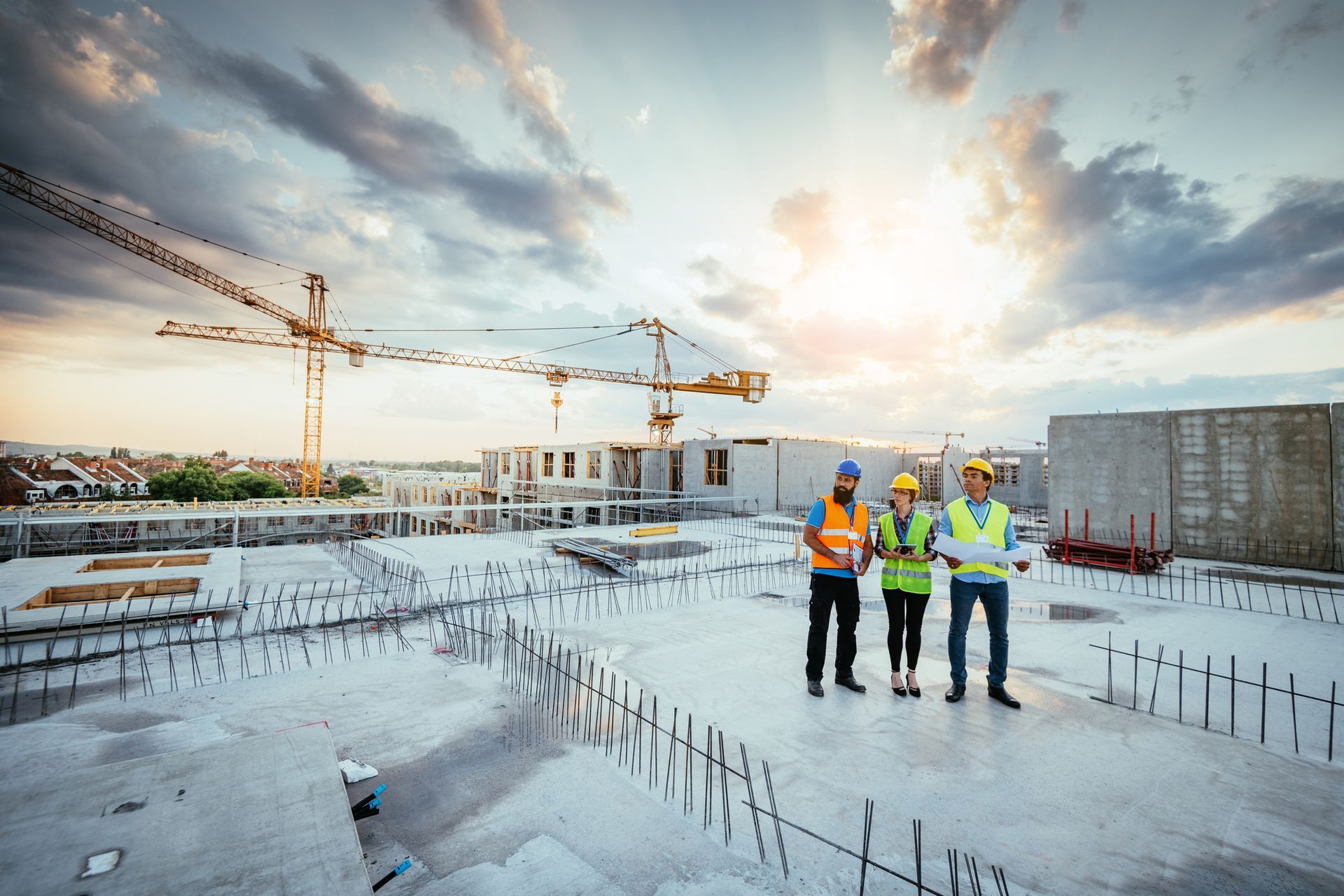 Employees in protective gear discussing the next phase of industrial construction at a busy site.