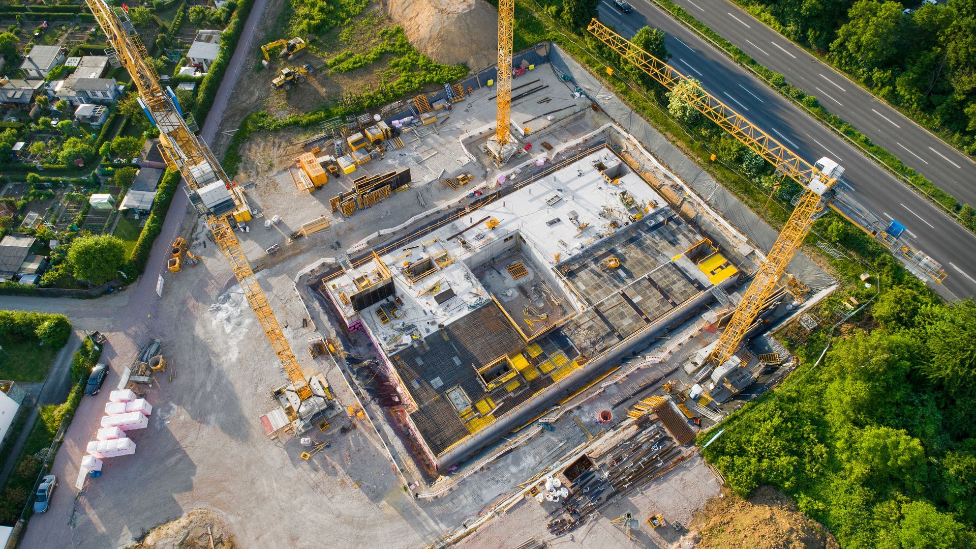 Aerial view of foundation work and equipment at an industrial construction site in progress.