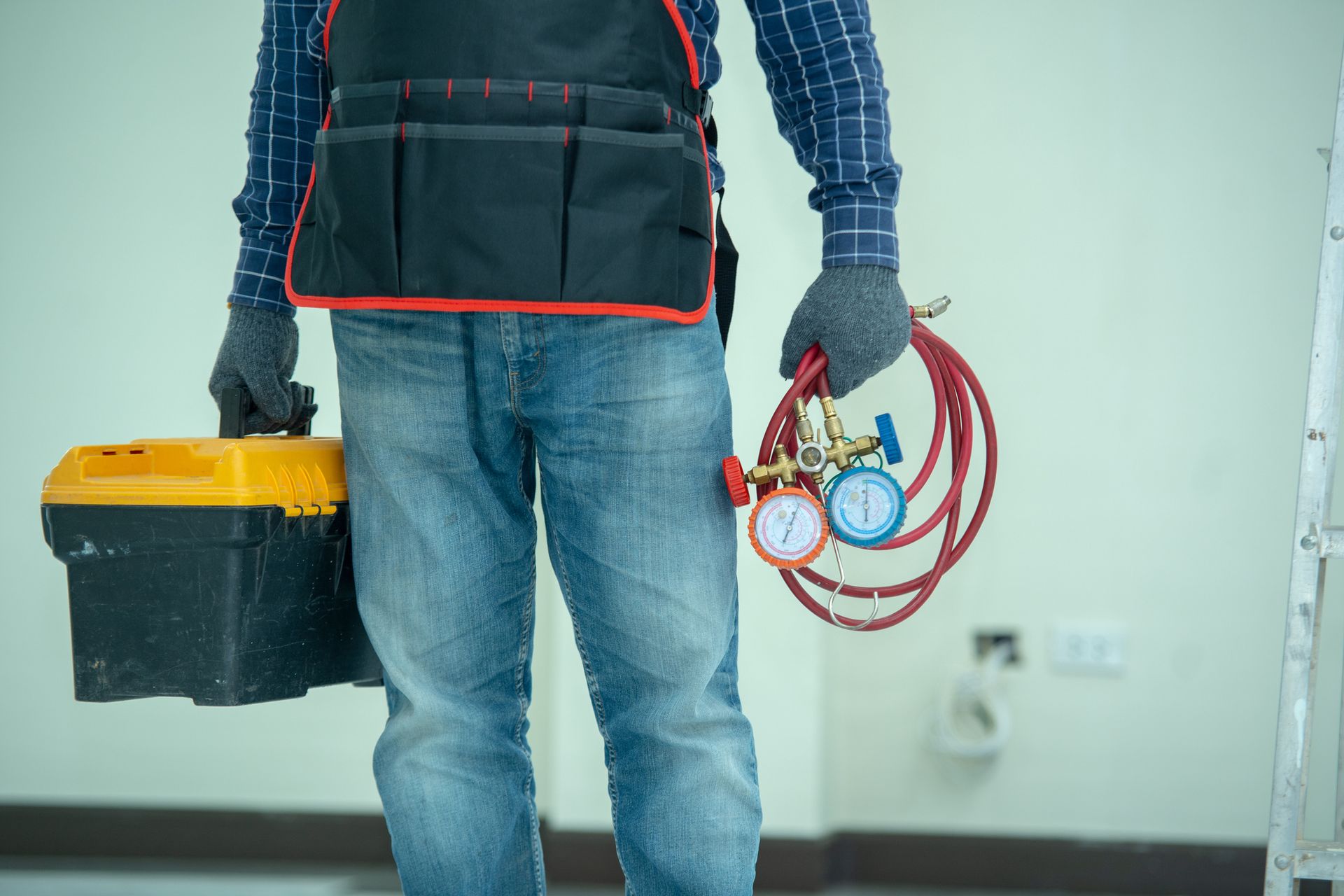 A man is holding a toolbox and a hose.