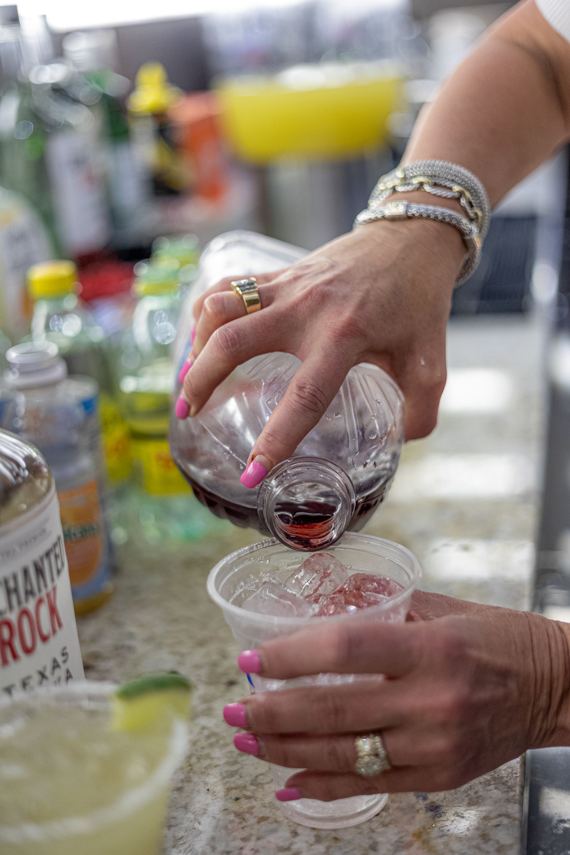 A woman is pouring a drink into a plastic cup.