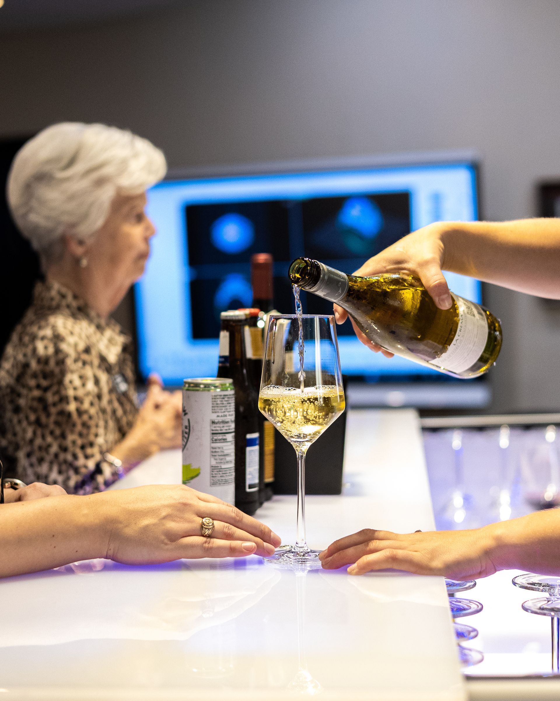 A person is pouring wine into a glass at a bar.