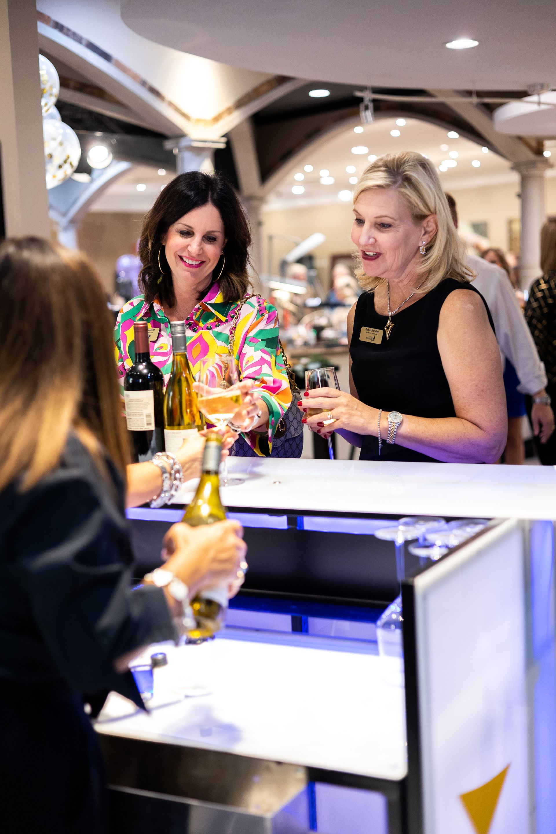 A group of women are sitting at a bar drinking wine.