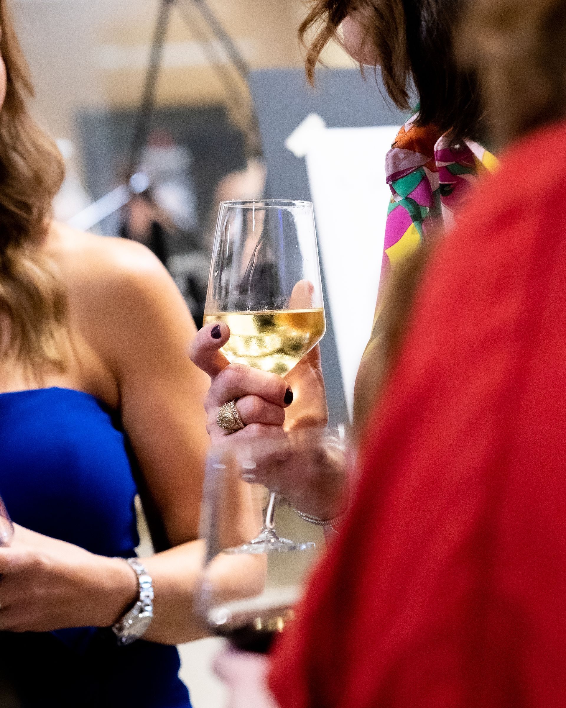 A woman in a blue dress is holding a glass of wine.