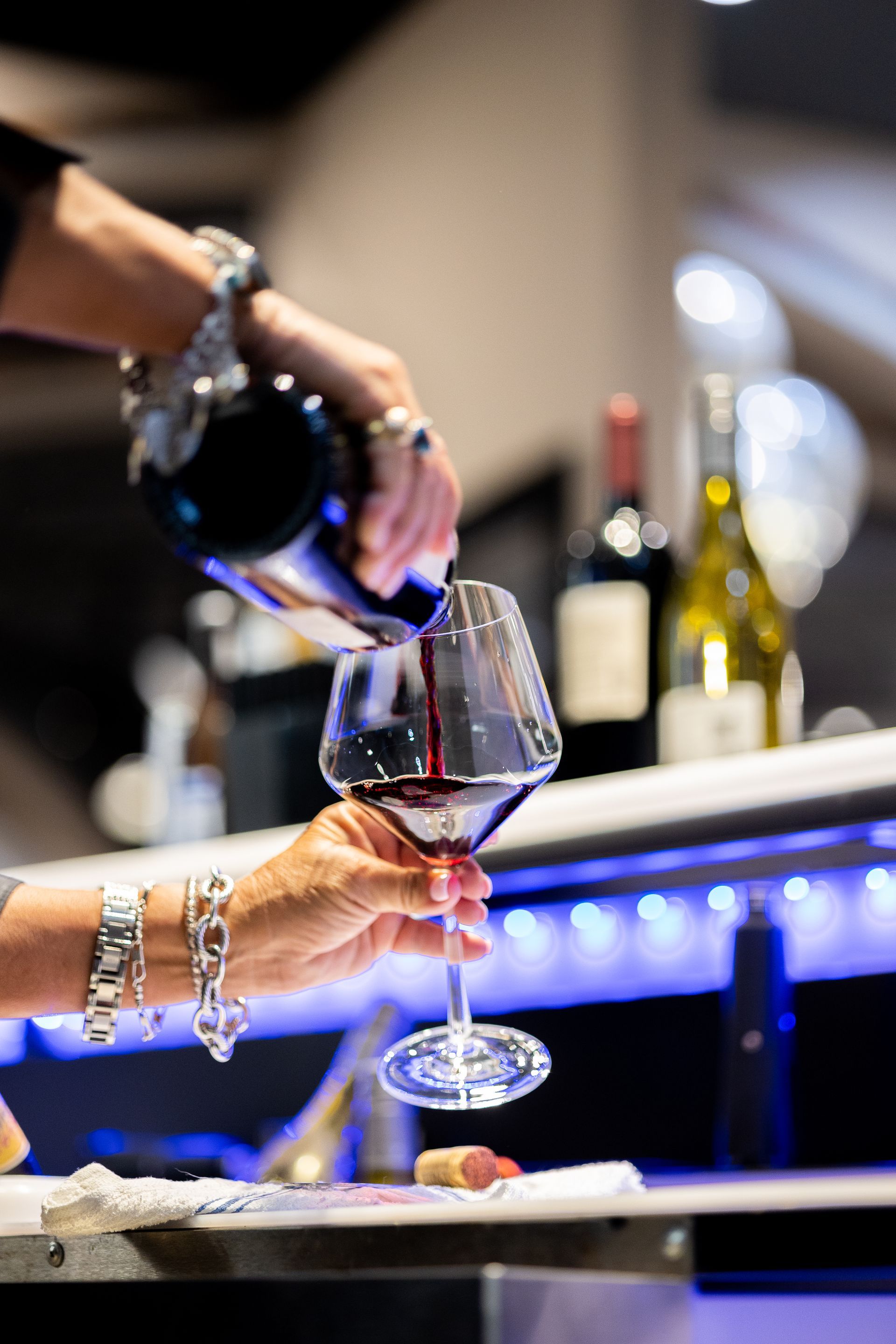 A person is pouring red wine into a glass.