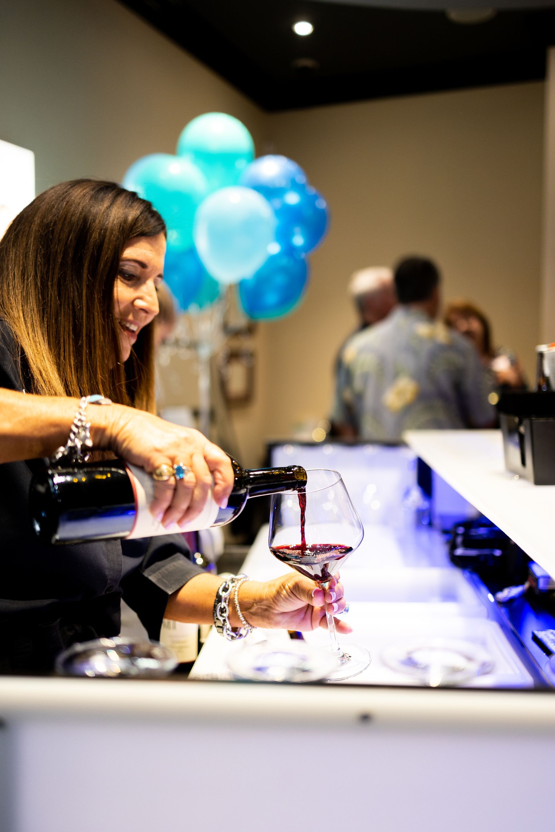 A woman is pouring wine into a glass at a bar.