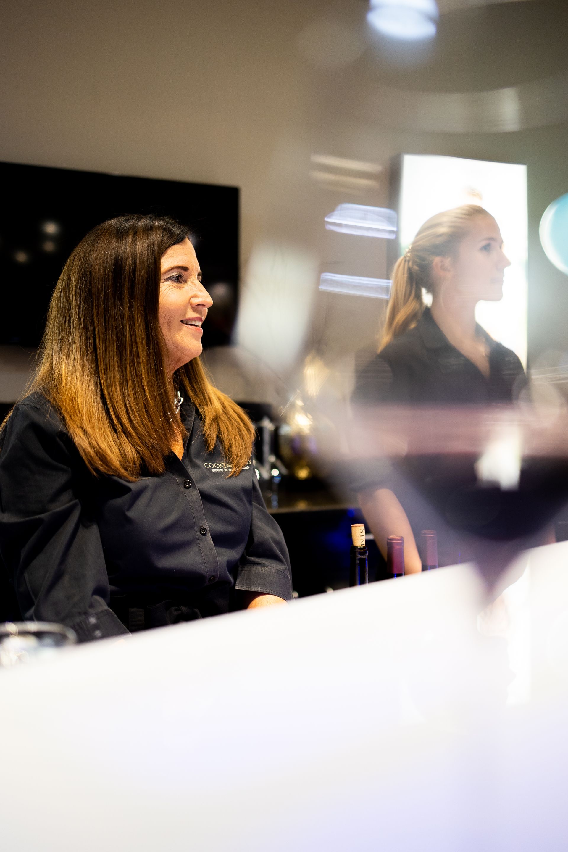 A woman is sitting at a table with a glass of wine.