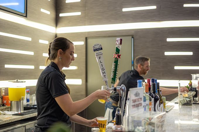 A woman is pouring beer into a glass at a bar.