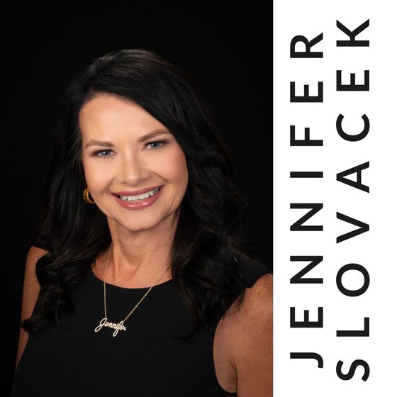 A woman in a black dress and necklace is smiling for the camera.