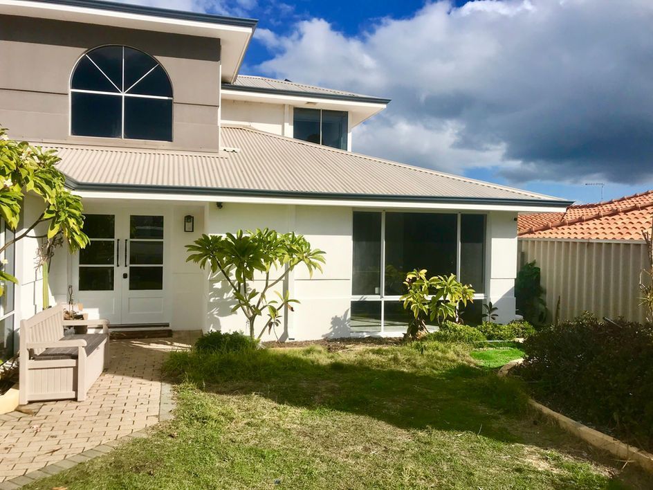 Suburban two-story house with a light gray roof and arched window.