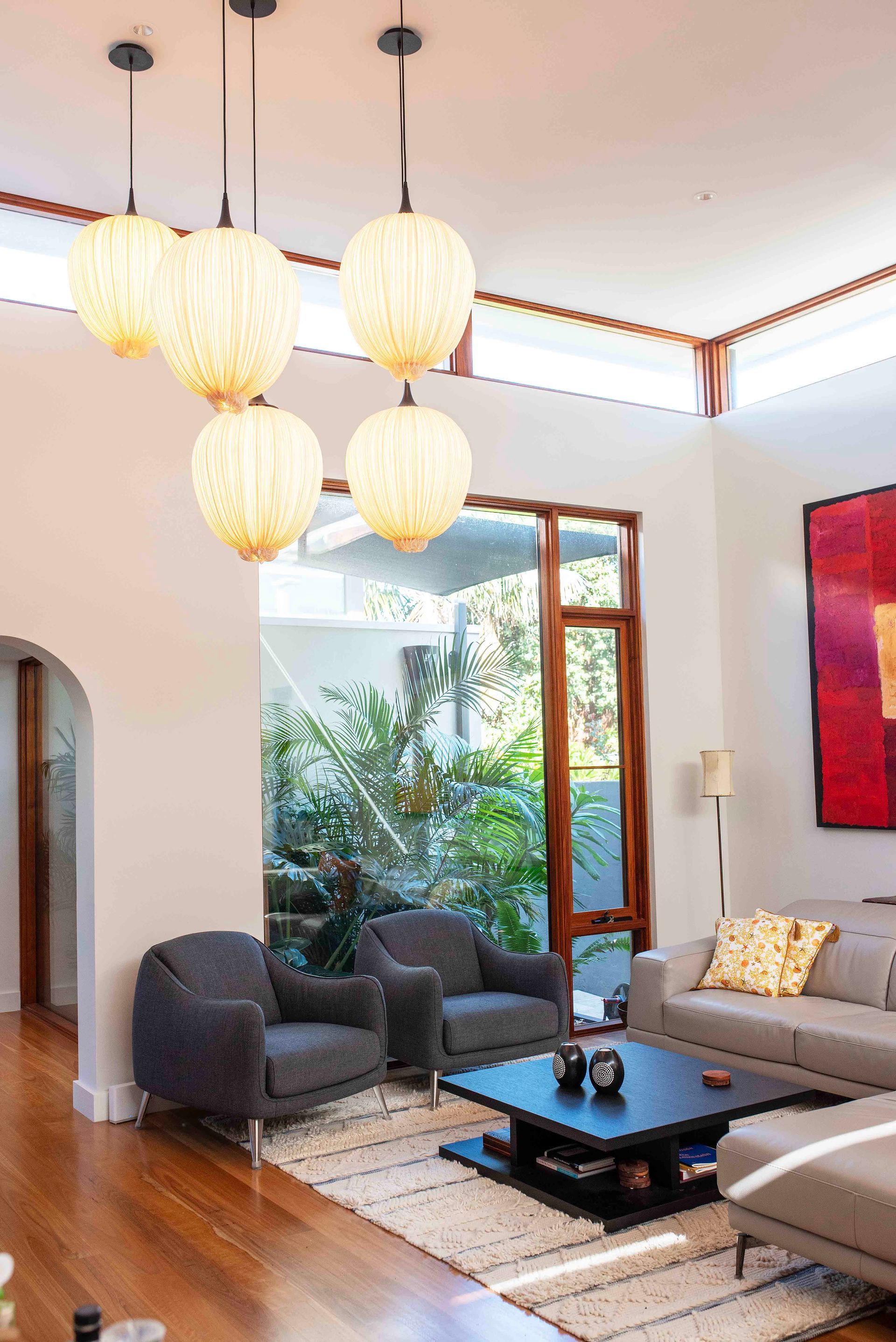 Close-up of four warm globe pendant lights hanging from a high ceiling.