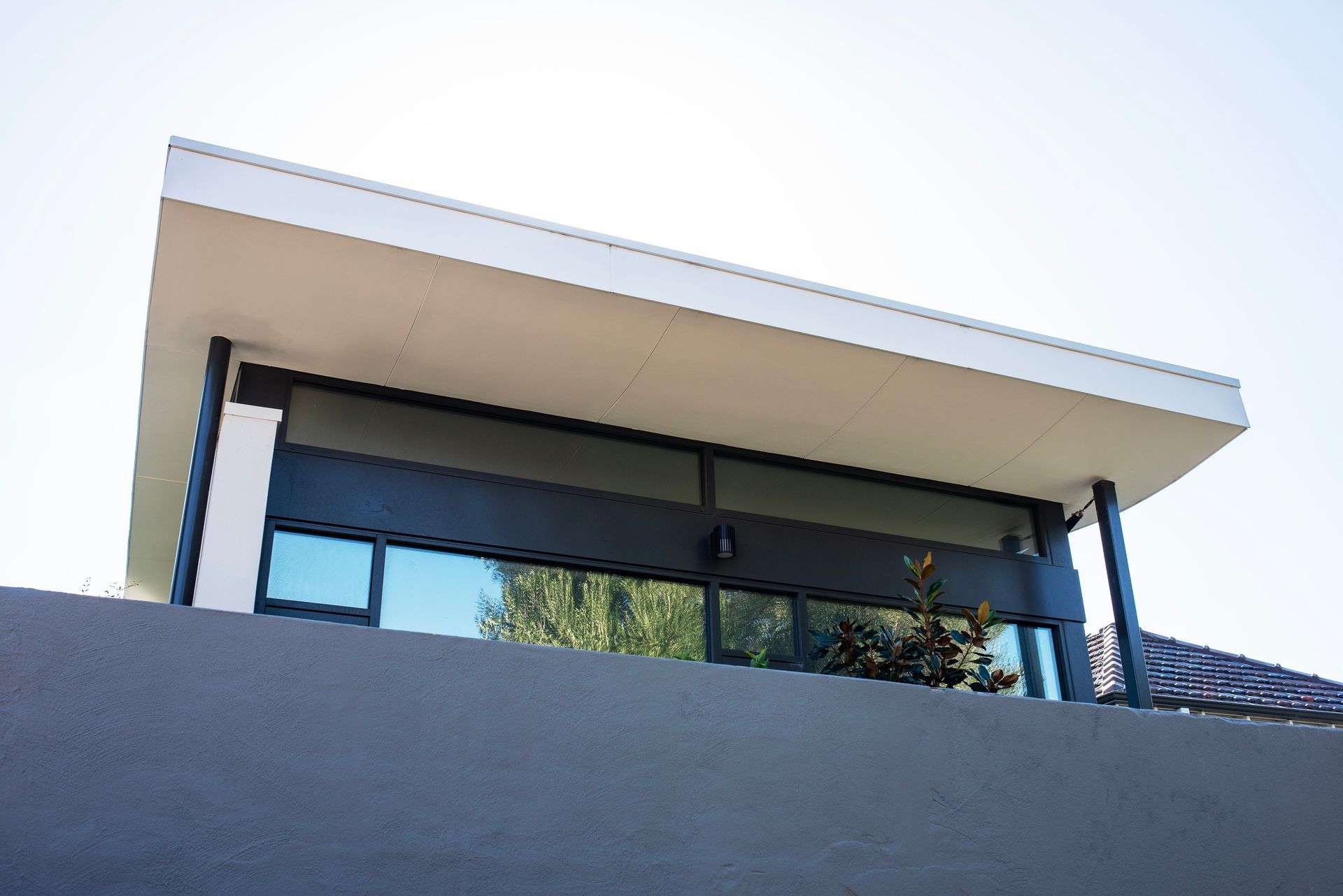 Exterior of a modern home with a flat roof overhang and strip window.