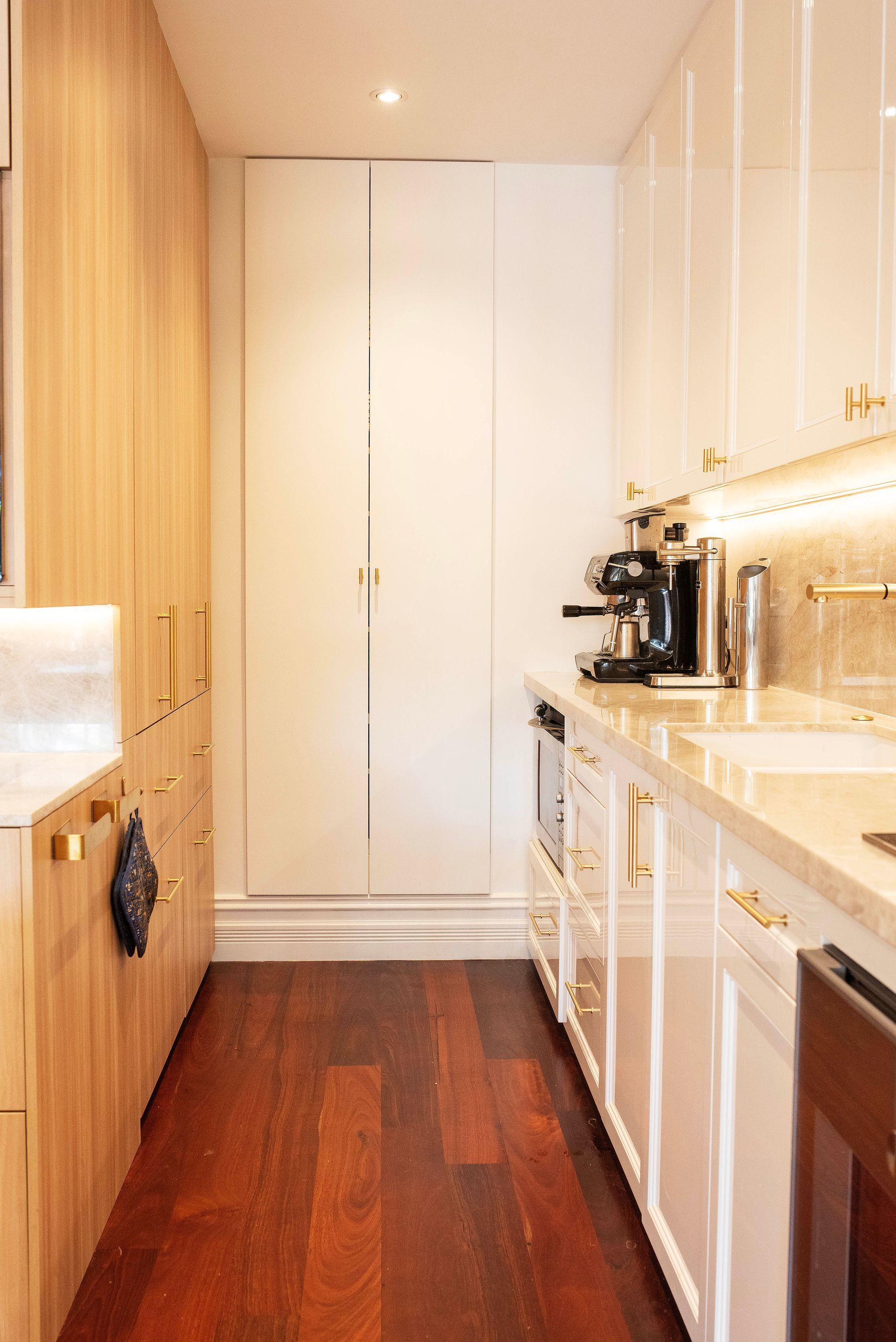Minimalist kitchen wall with white glossy cabinets and light wood paneling.