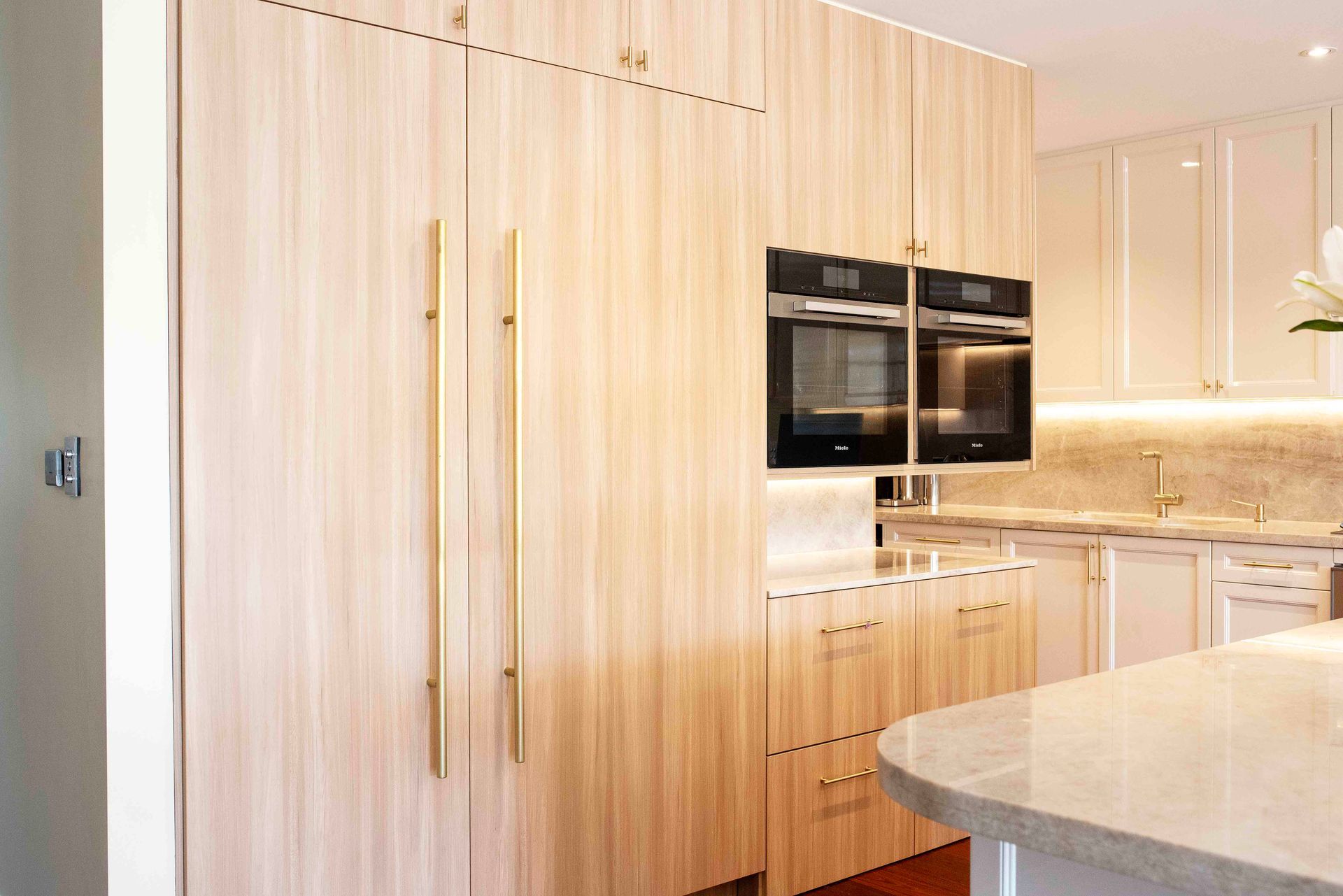 Kitchen view showing wood grain cabinets, stainless steel hardware, and built-in ovens.