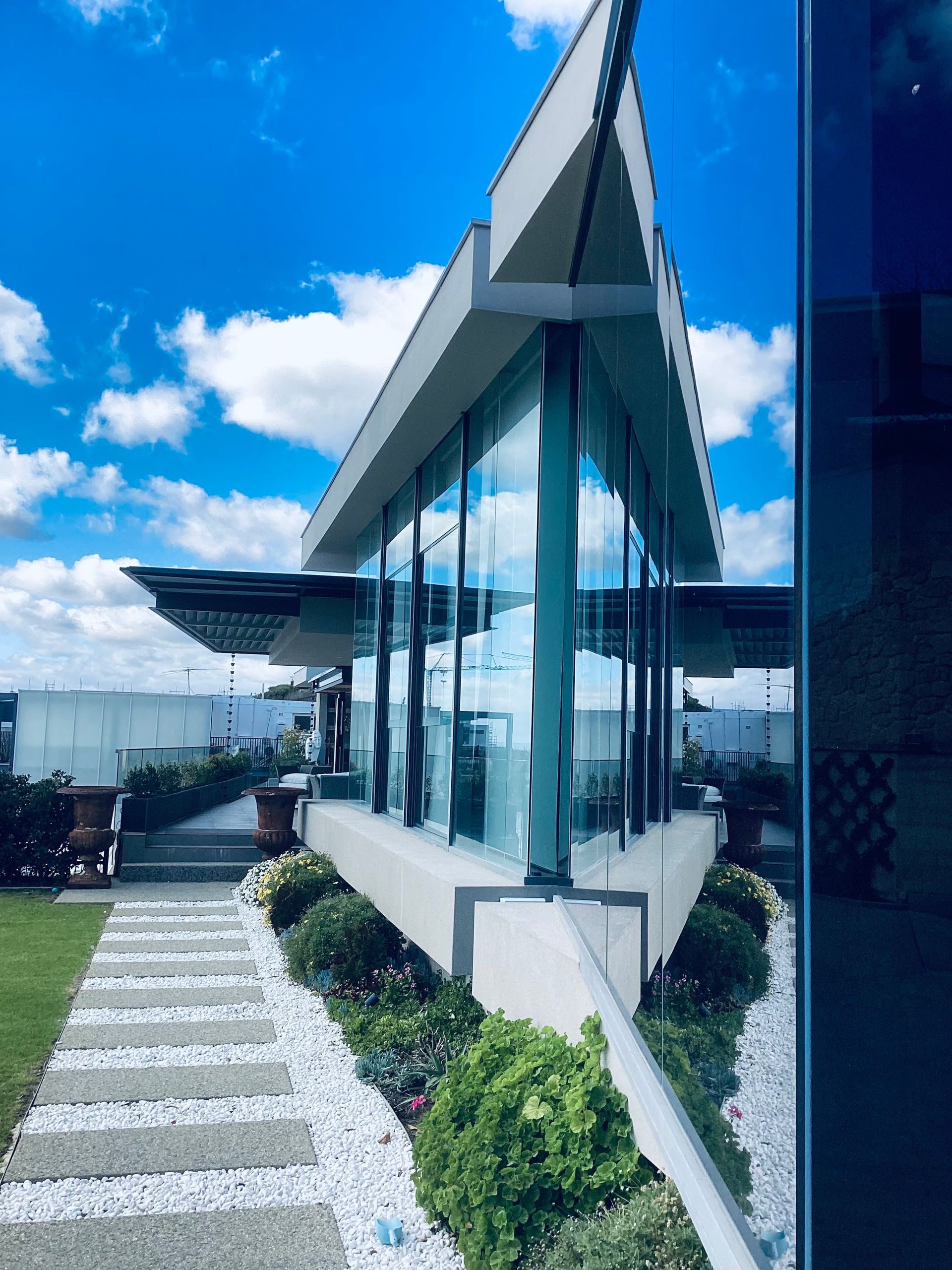 Modern glass building exterior against a blue sky with clouds.