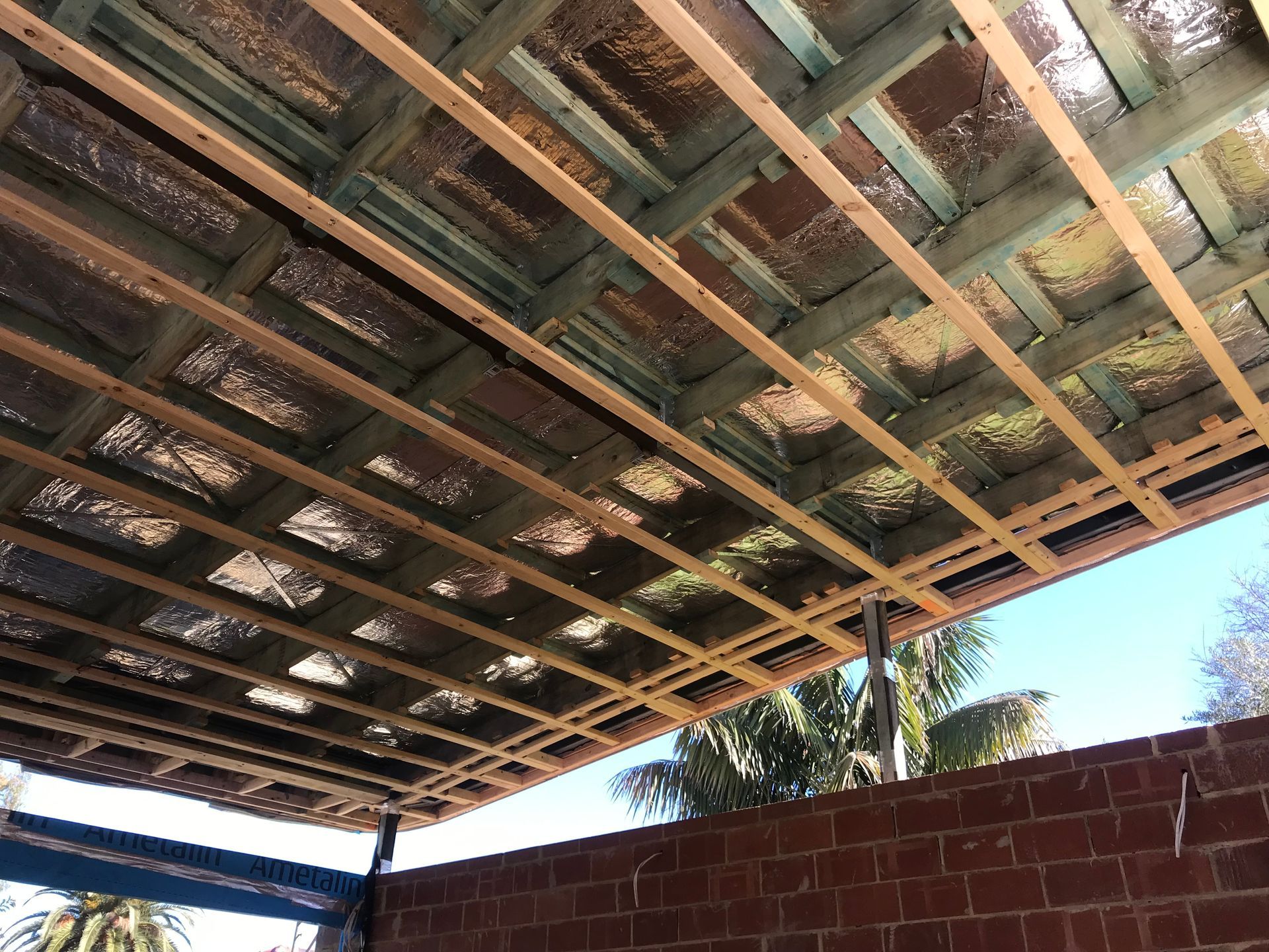 Close-up view of the exposed wooden beams and insulation beneath a patio roof.