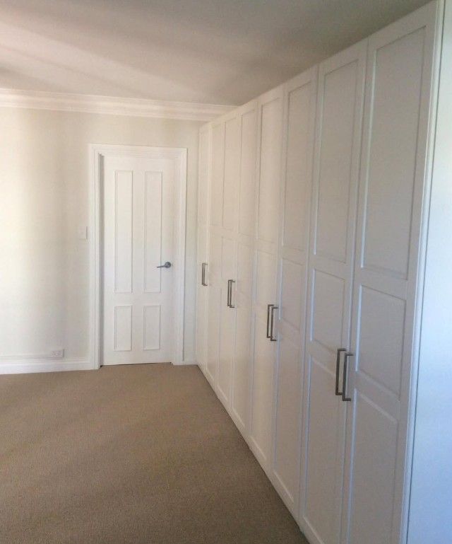White built-in cabinets and a door in a freshly finished interior room.