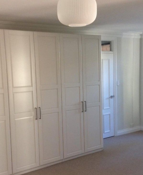 White built-in cabinetry beneath a round ceiling light in a renovated interior room.