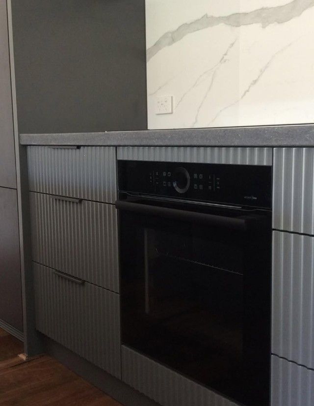 Kitchen area with marble-style backsplash and ribbed panel design.