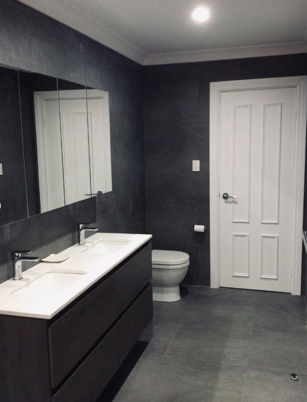 Renovated room with dark textured walls, white door, and ceiling lights.