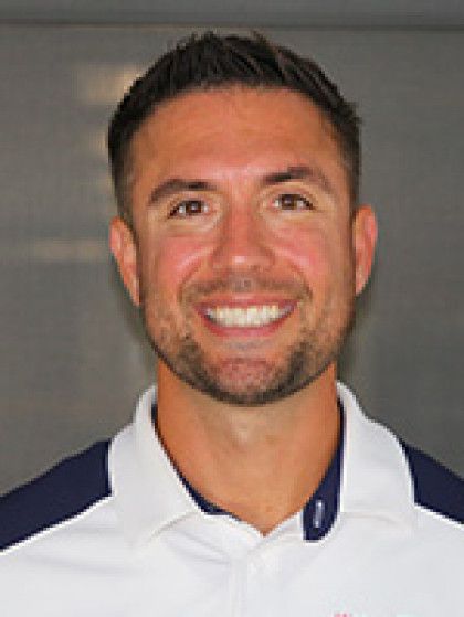 A man with a beard and a white shirt is smiling for the camera.