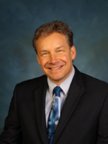 A man in a suit and tie is smiling for the camera