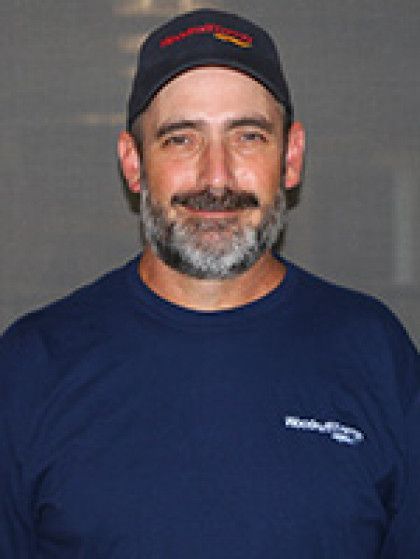 A man with a beard and a hat is wearing a blue shirt.