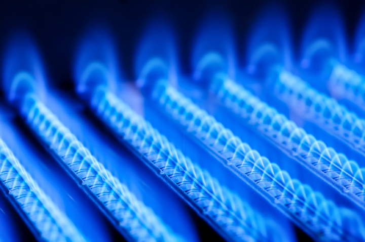 A close up of a gas burner with blue flames coming out of it.