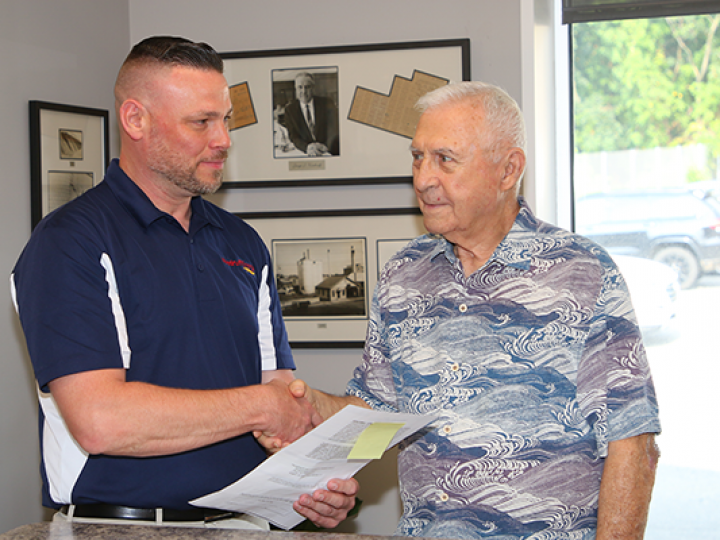 Two men shaking hands in a room with pictures on the wall