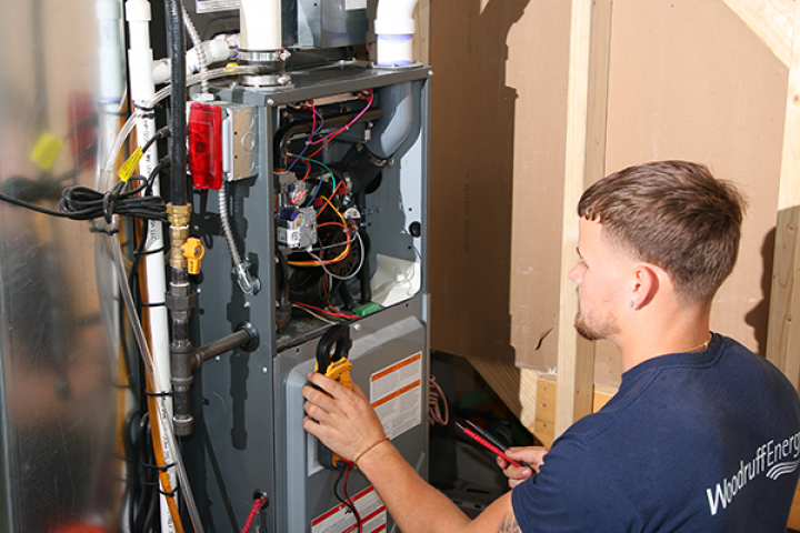 A man is working on an air conditioner in a garage.