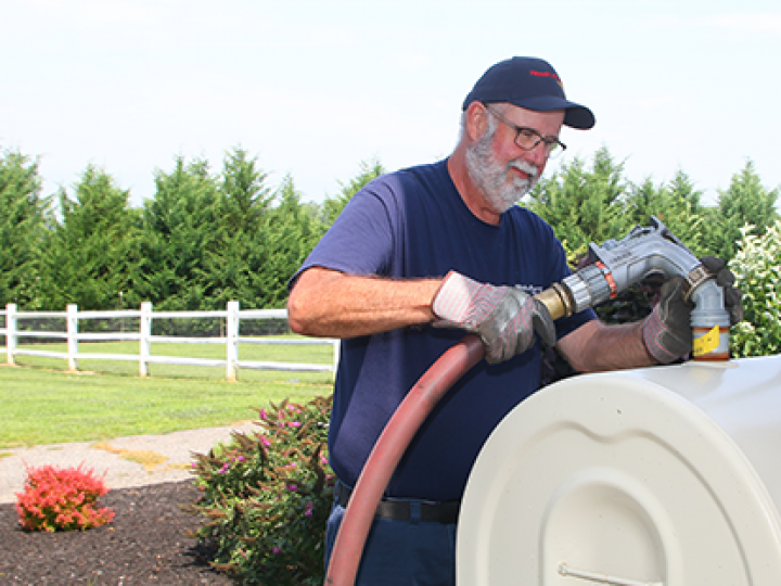 A man is pumping gas into a tank with a hose