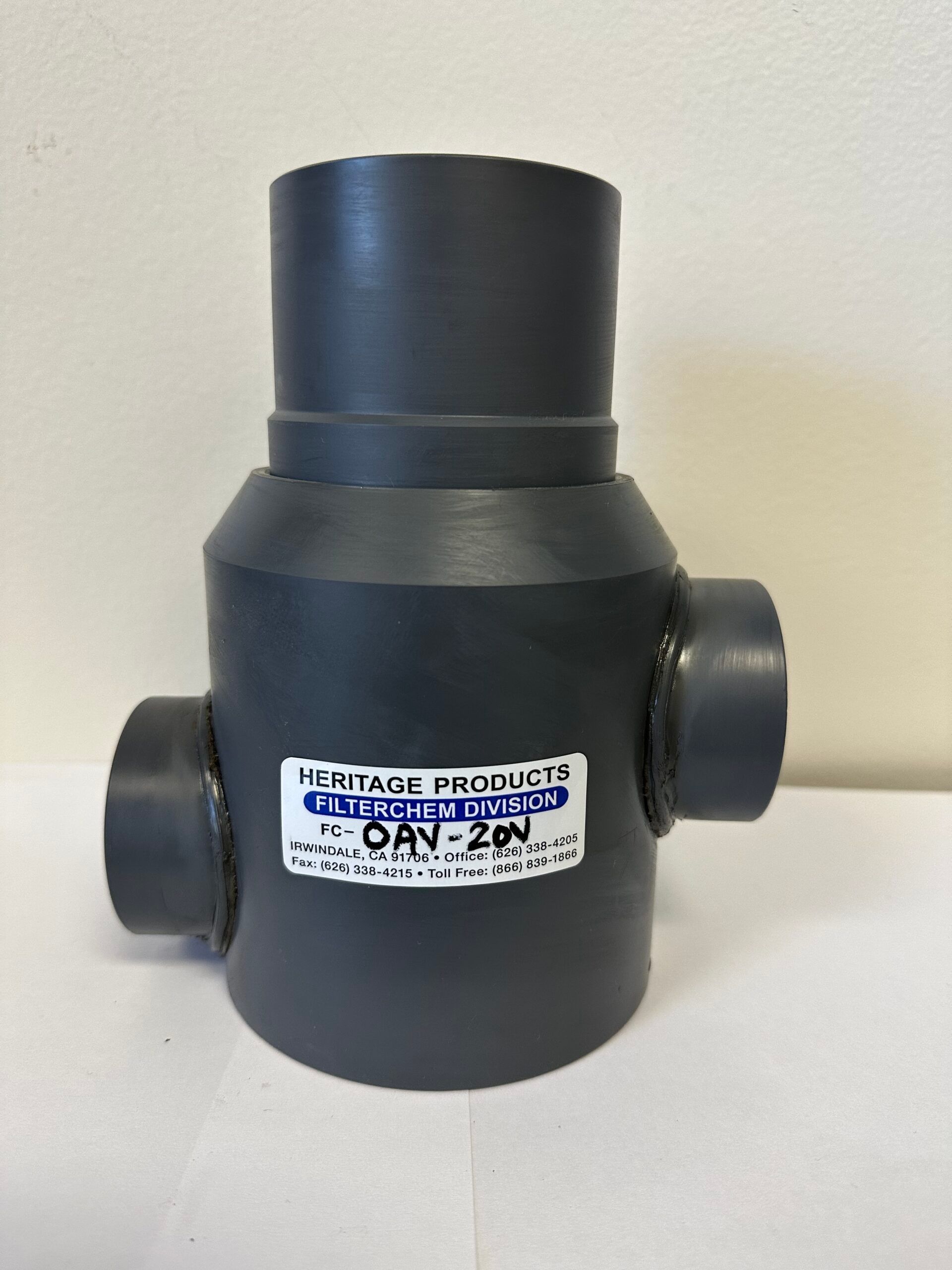 A black plastic pipe with a label on it is sitting on a white table.