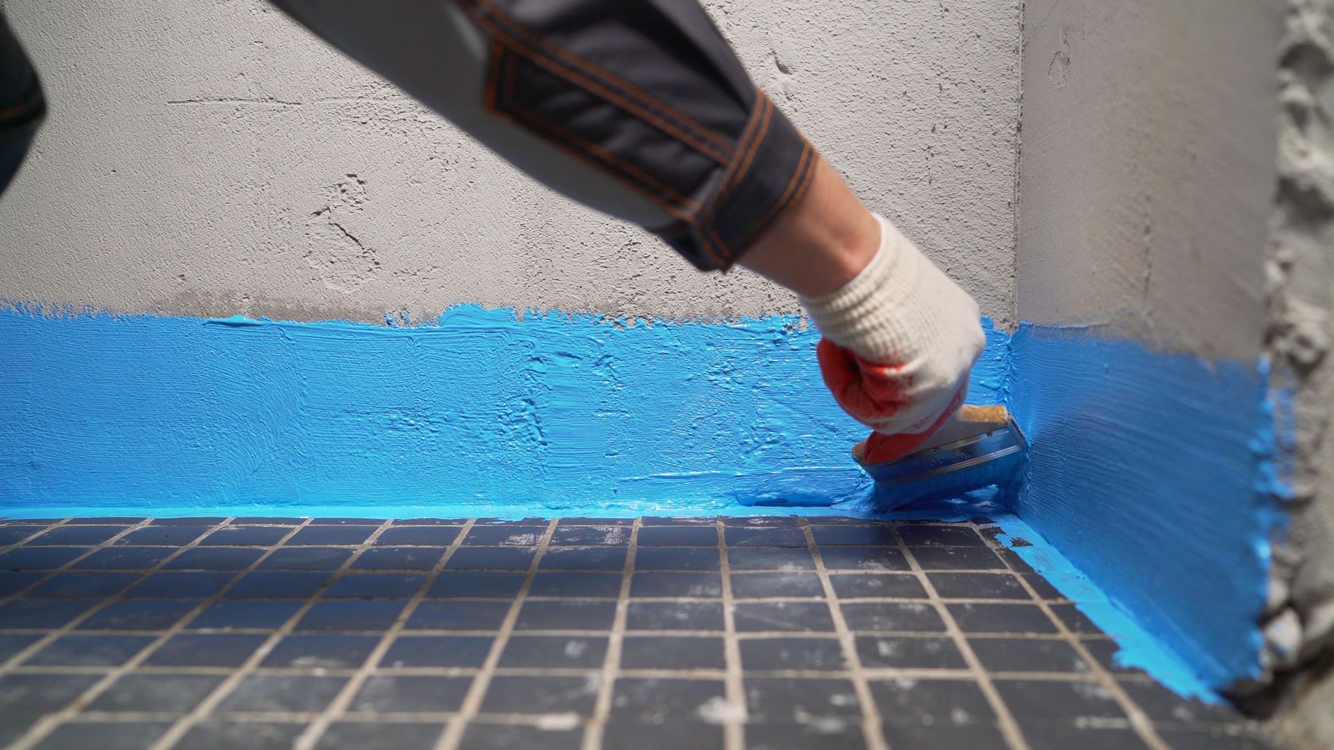 Person painting a wall blue near the floor with a brush. Person painting a wall blue near the floor with a brush.