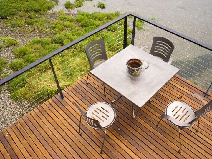 A wooden deck with a table and chairs and a cup of coffee on it